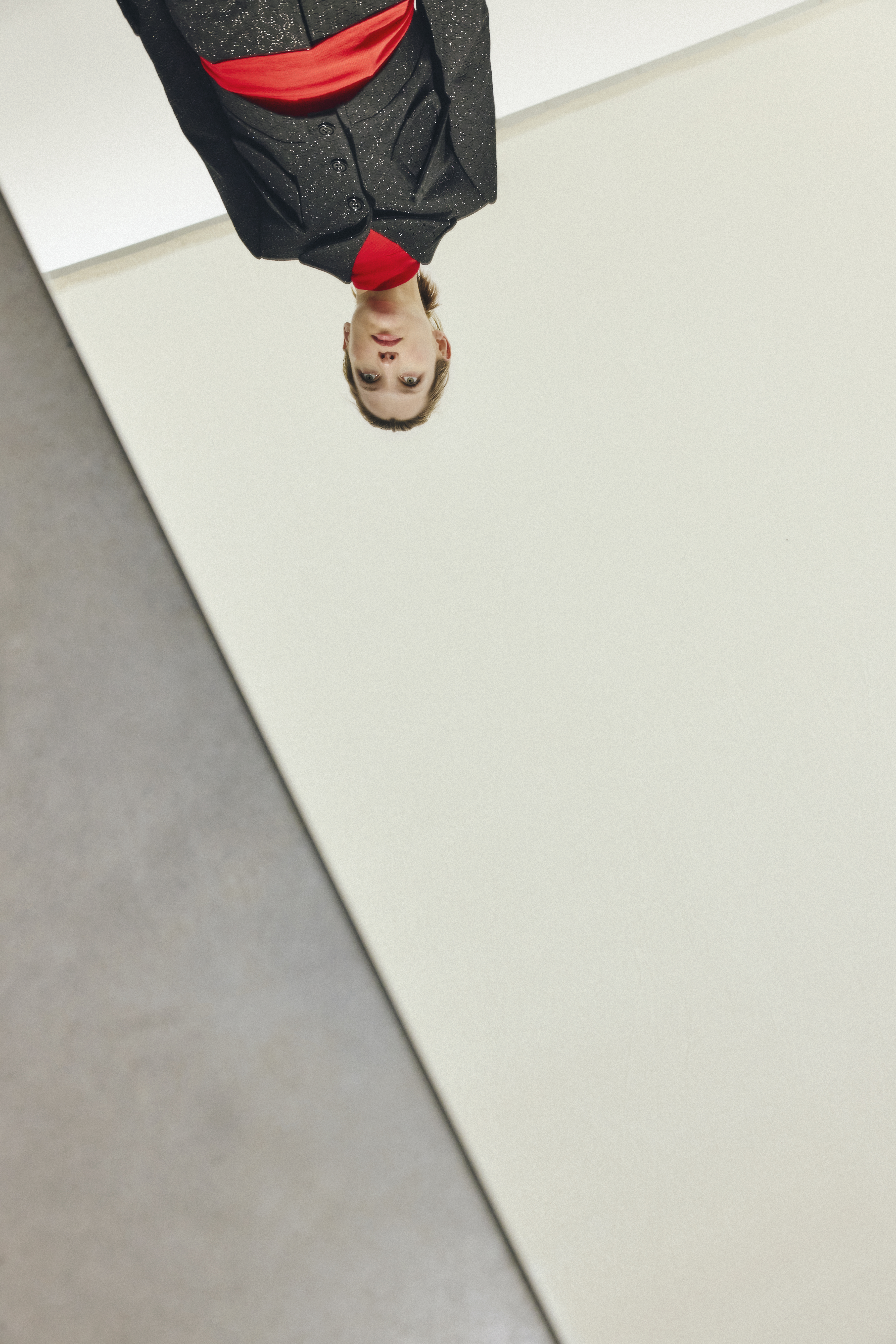 model is wearing a black punto suit with a broken suit and wide leg trousers also a red turtleneck underneath