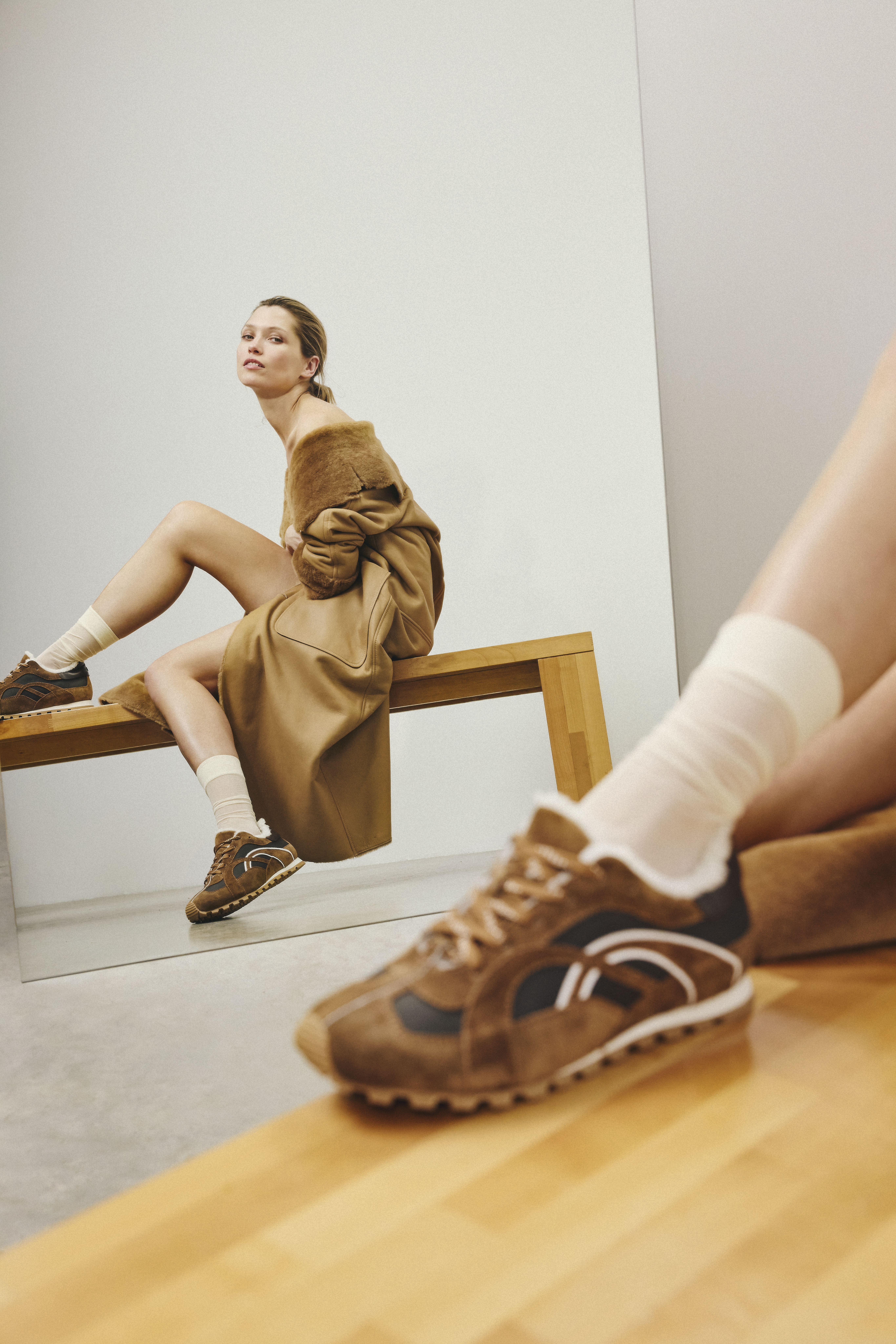 model is wearing a brown leather coat with a furry collar and brown sporty sneaker 