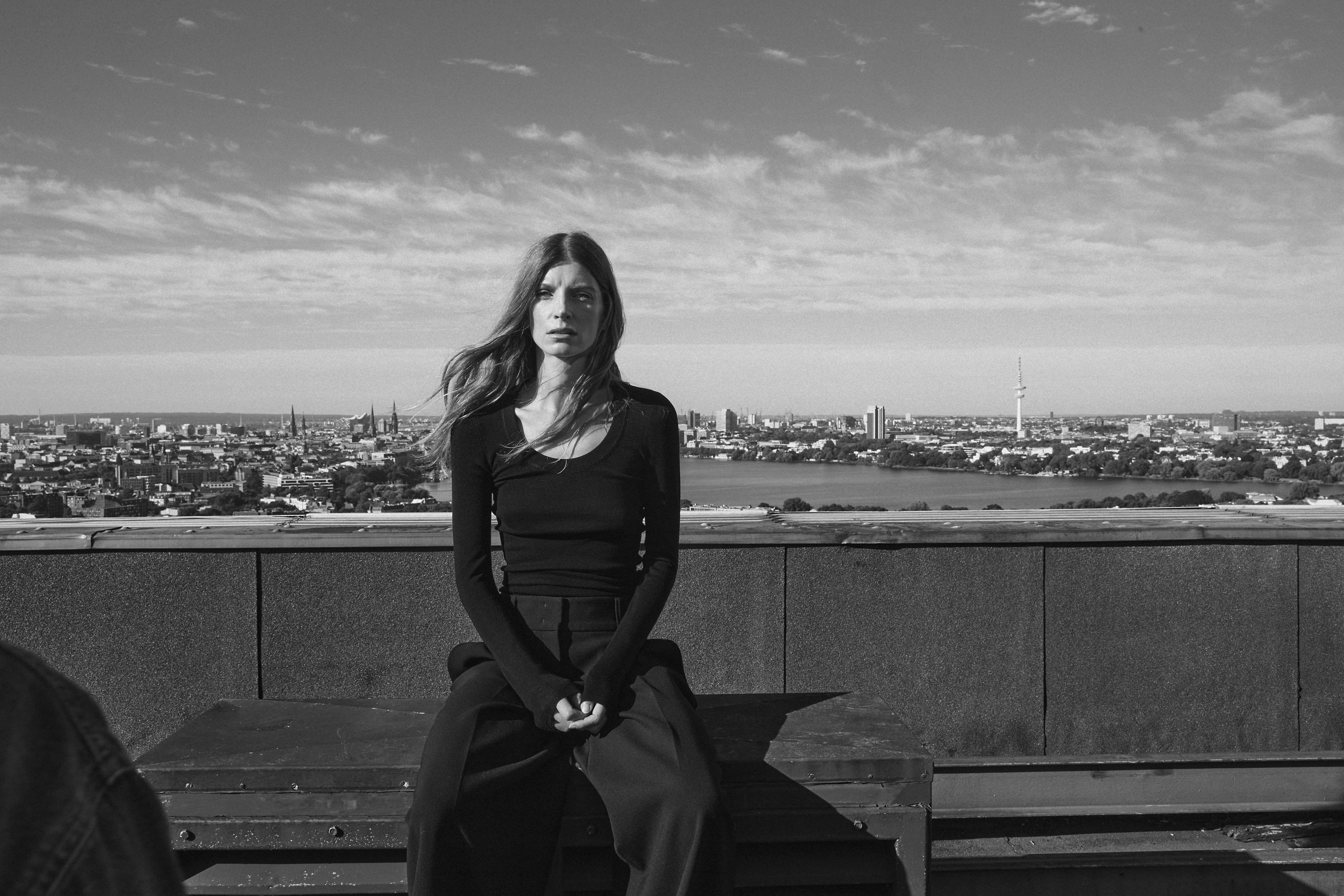 A woman sitting on a bench wearing a black top and black pants