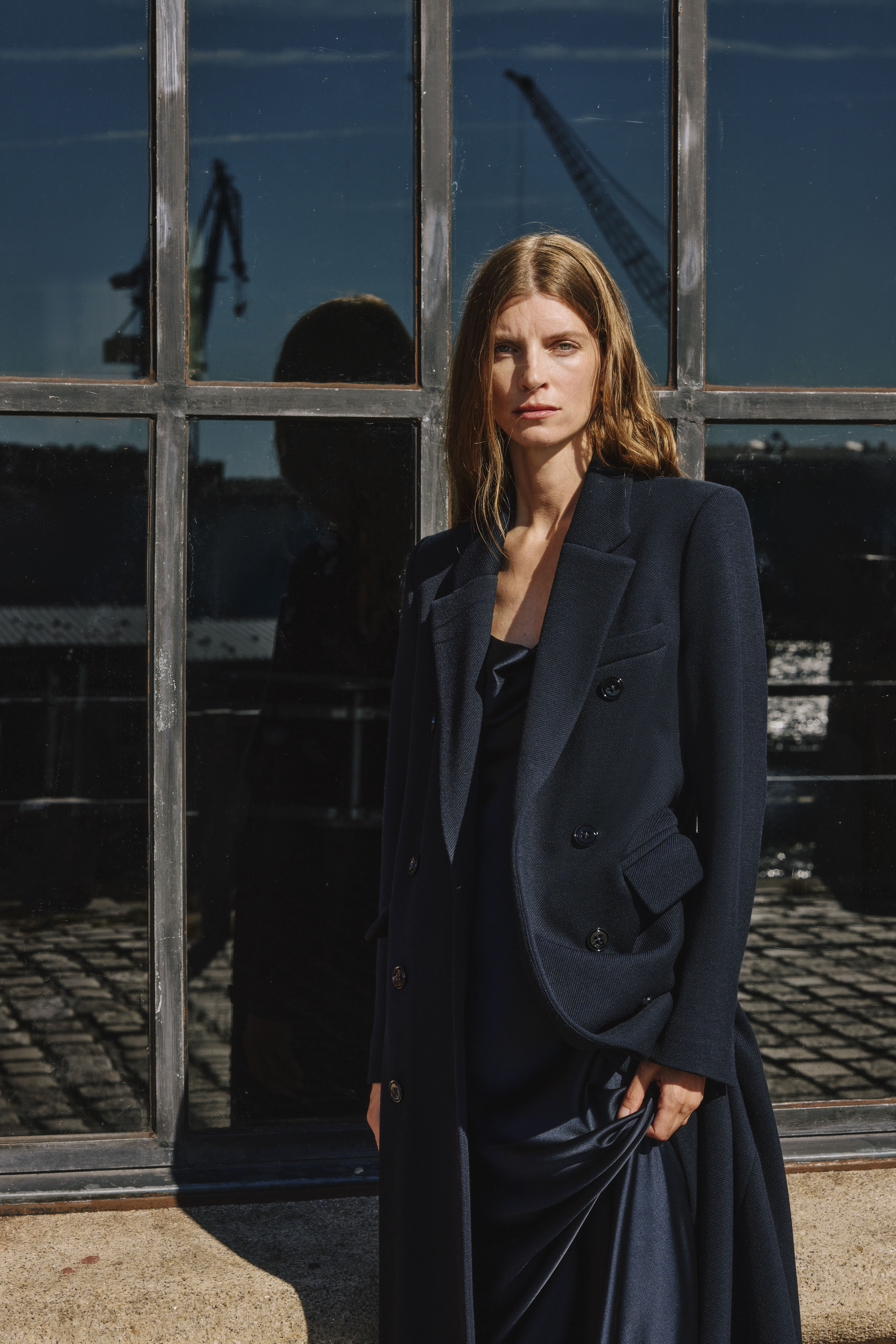 a woman wearing a blue long coat and blue satin blouses