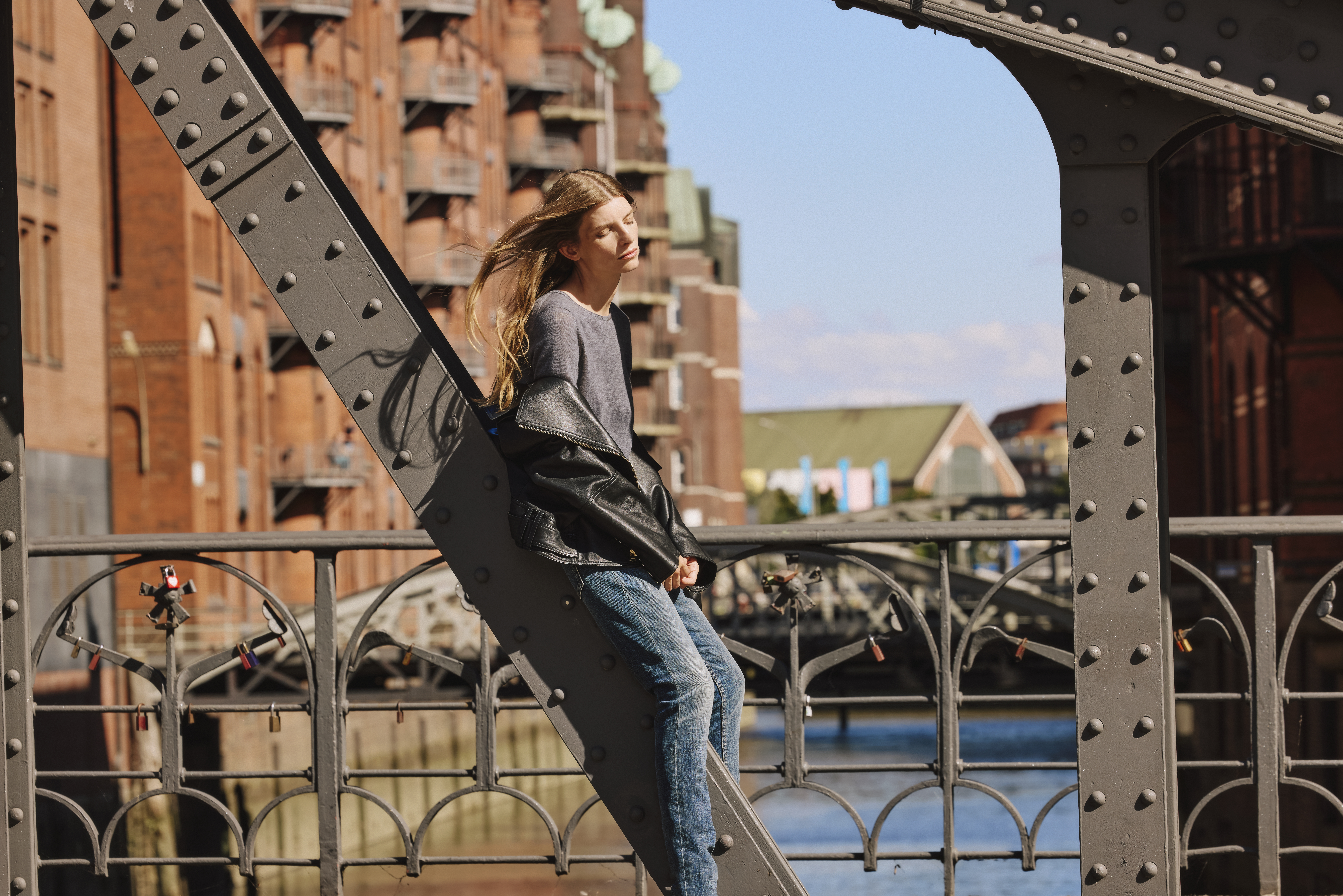 woman wearing a black leather jacket and a grey sweater with a blue jeans 