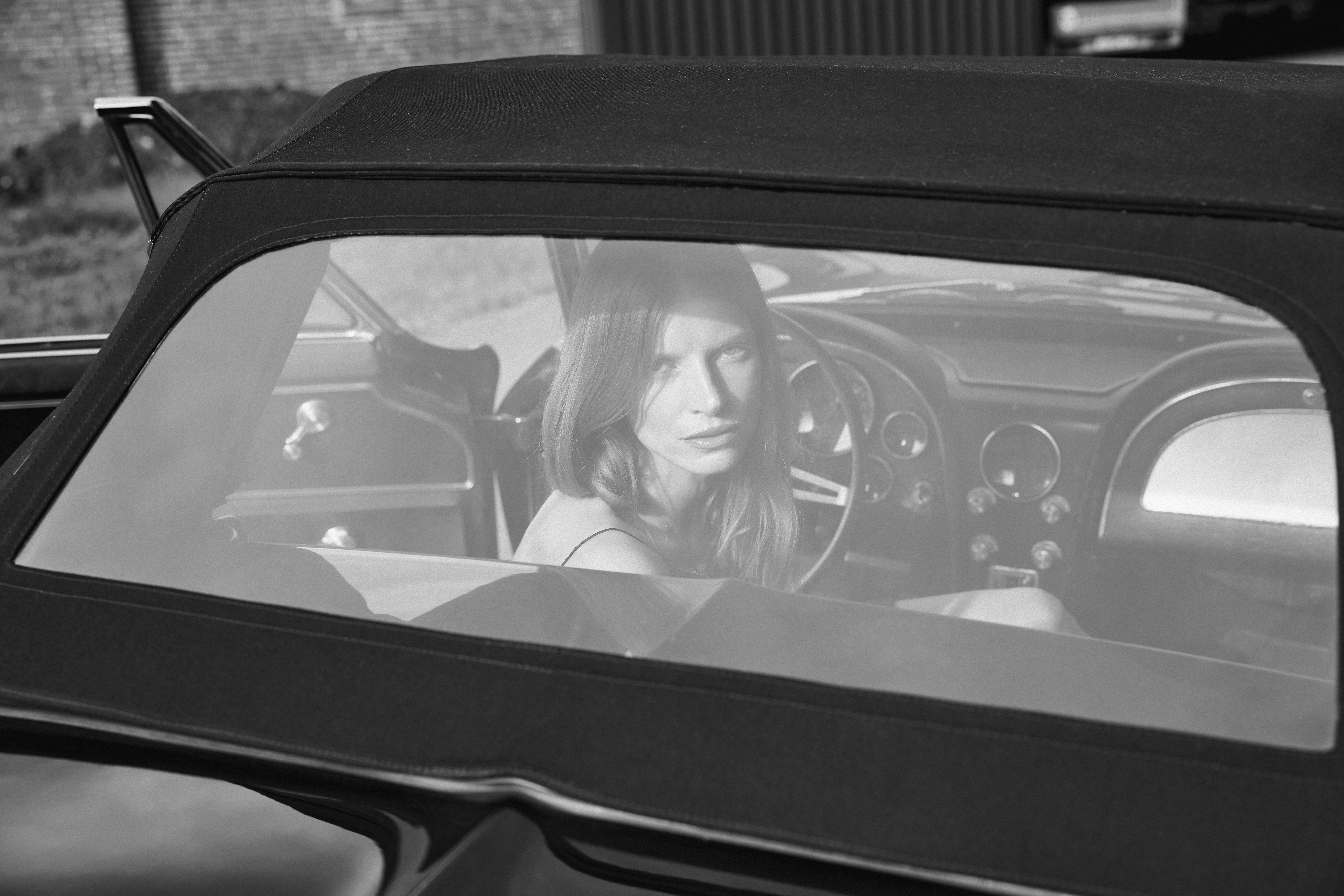 a woman is looking back through the rear window in a black car