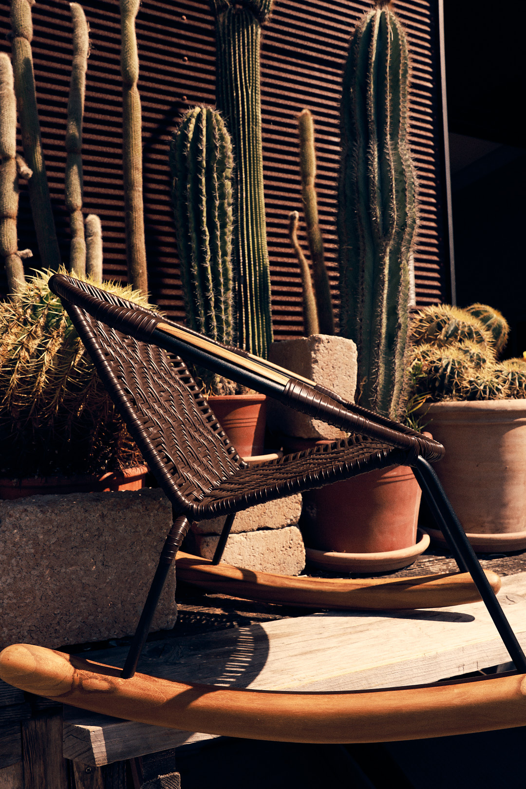 Brown Rocking Chair in a sideprofile standing in front of plants